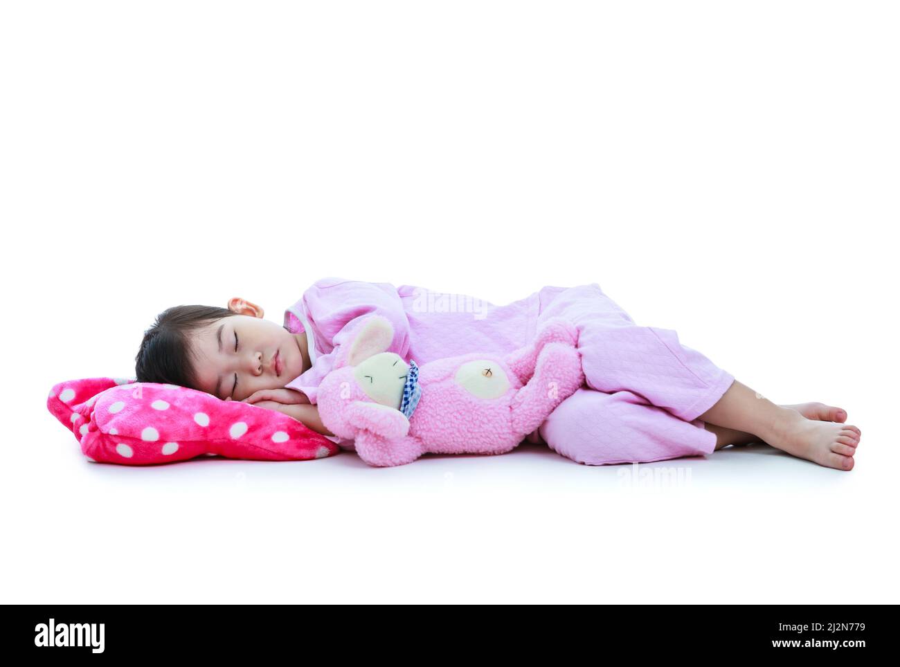 Ganzkörper. Gesundes Kinderkonzept. Asiatisches Kind schläft friedlich. Liebenswert Mädchen in rosa Schlafanzug unter ein Nickerchen. Isoliert auf weißem Hintergrund. Stockfoto