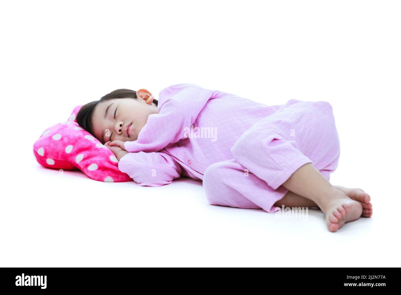 Ganzkörper. Gesundes Kinderkonzept. Asiatisches Kind schläft friedlich. Liebenswert Mädchen in rosa Schlafanzug unter ein Nickerchen. Isoliert auf weißem Hintergrund. Stockfoto