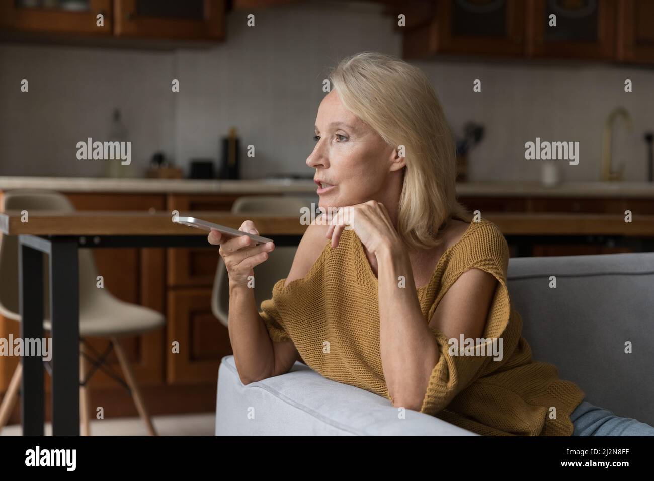 Seriöse Frau, die einen Anruf per Mobiltelefon über den Lautsprecher hat und Audio aufnimmt Stockfoto