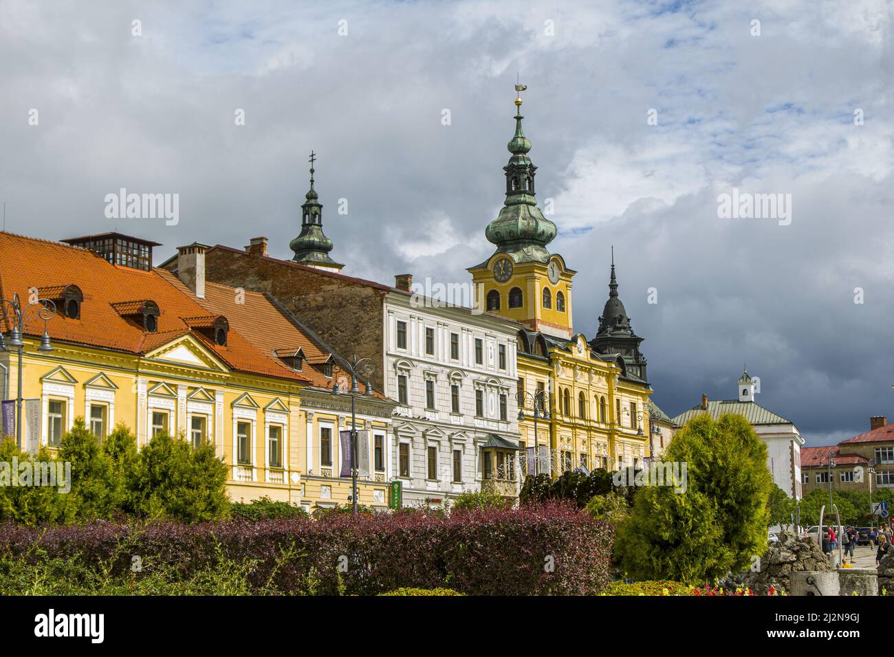 Banska Bystrica, Slowakei - 17. August 2021: Blick auf den SNP-Platz - bunte historische Gebäude, Schloss Mestsky Grad, grüne Bäume und Menschen, die aro spazieren gehen Stockfoto