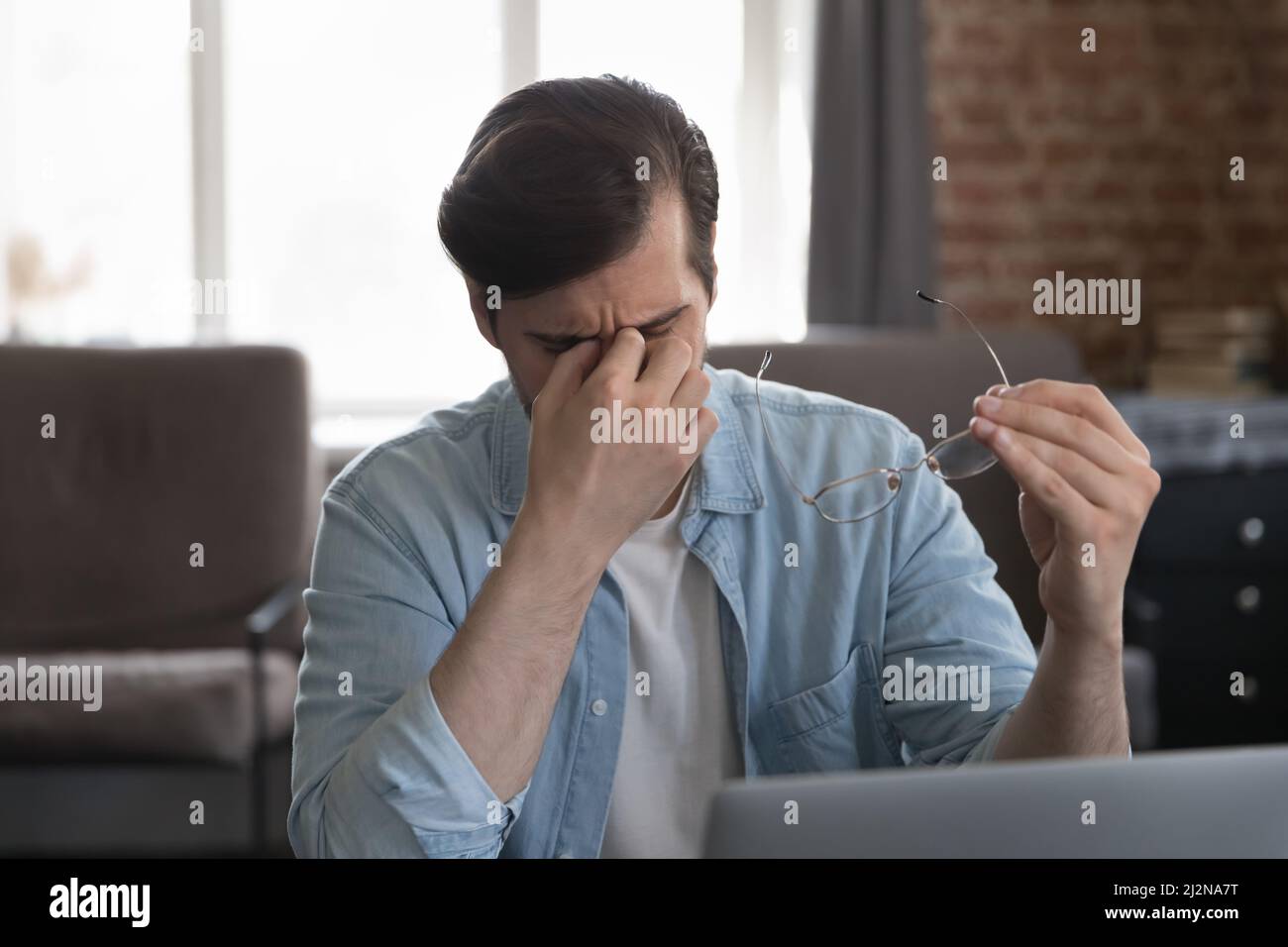 Frustrierte Mitarbeiter, die im Heimbüro am Laptop arbeiten Stockfoto