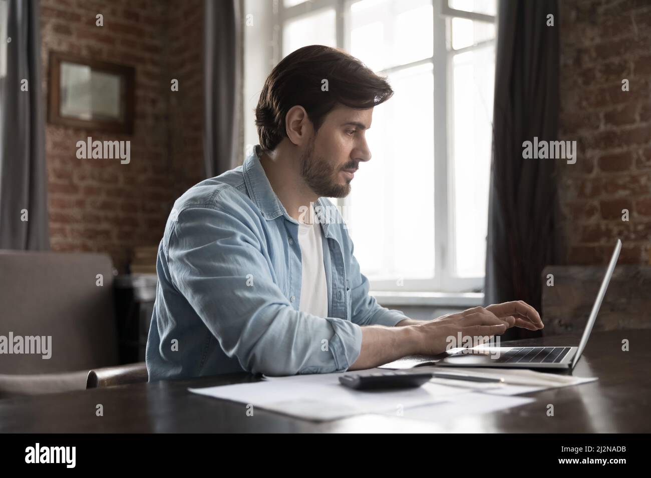 Fokussierter Mieter Mann, der Inlandsrechnungen bezahlt, mit Online-Zahlungs-App Stockfoto