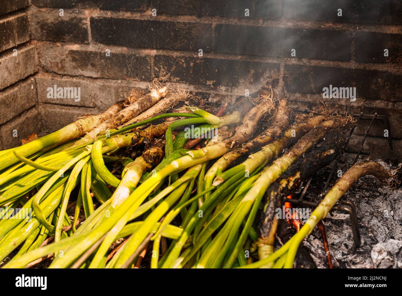 Nahaufnahme eines Stapels von Kalotten oder süßen Zwiebeln, die im Grill gekocht werden. Typisch für Katalonien, Spanien Stockfoto