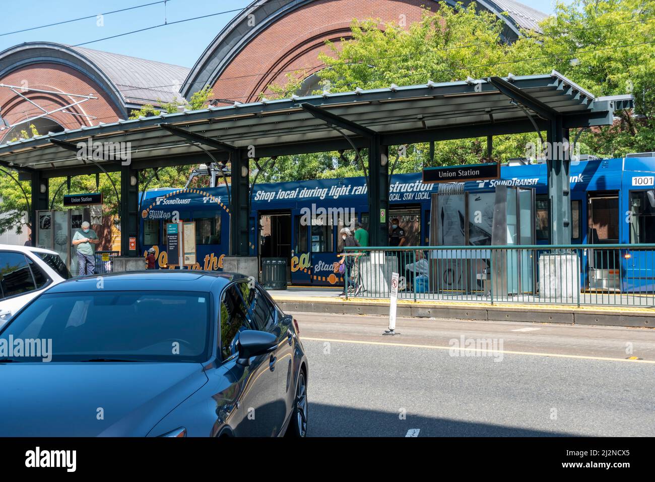Tacoma, WA USA - ca. August 2021: Straßenansicht von Personen, die einen elektrischen Schienenbus von Sound Transit in der Innenstadt verlassen und besteigen. Stockfoto
