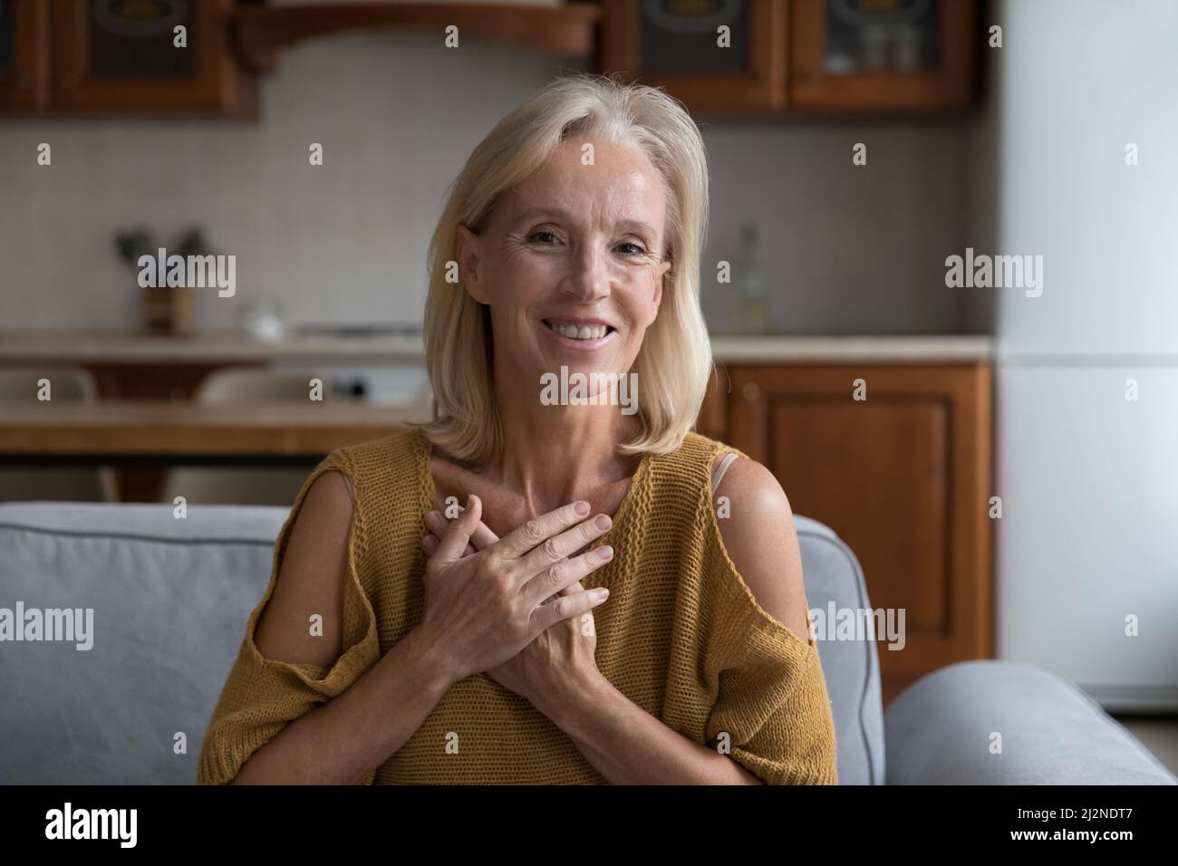 Glücklich dankbar reifen 50s Dame posiert auf Hause Couch Stockfoto