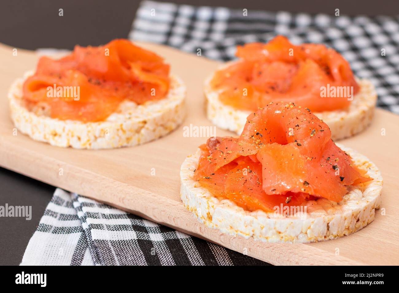 Leckere Reiskuchen-Sandwiches mit frischen Lachsscheiben auf Holzschneidebrette. Einfache Frühstück und Diät-Essen. Knäckebrot mit rotem Fisch. Gesunder Ernährungs-Snack Stockfoto