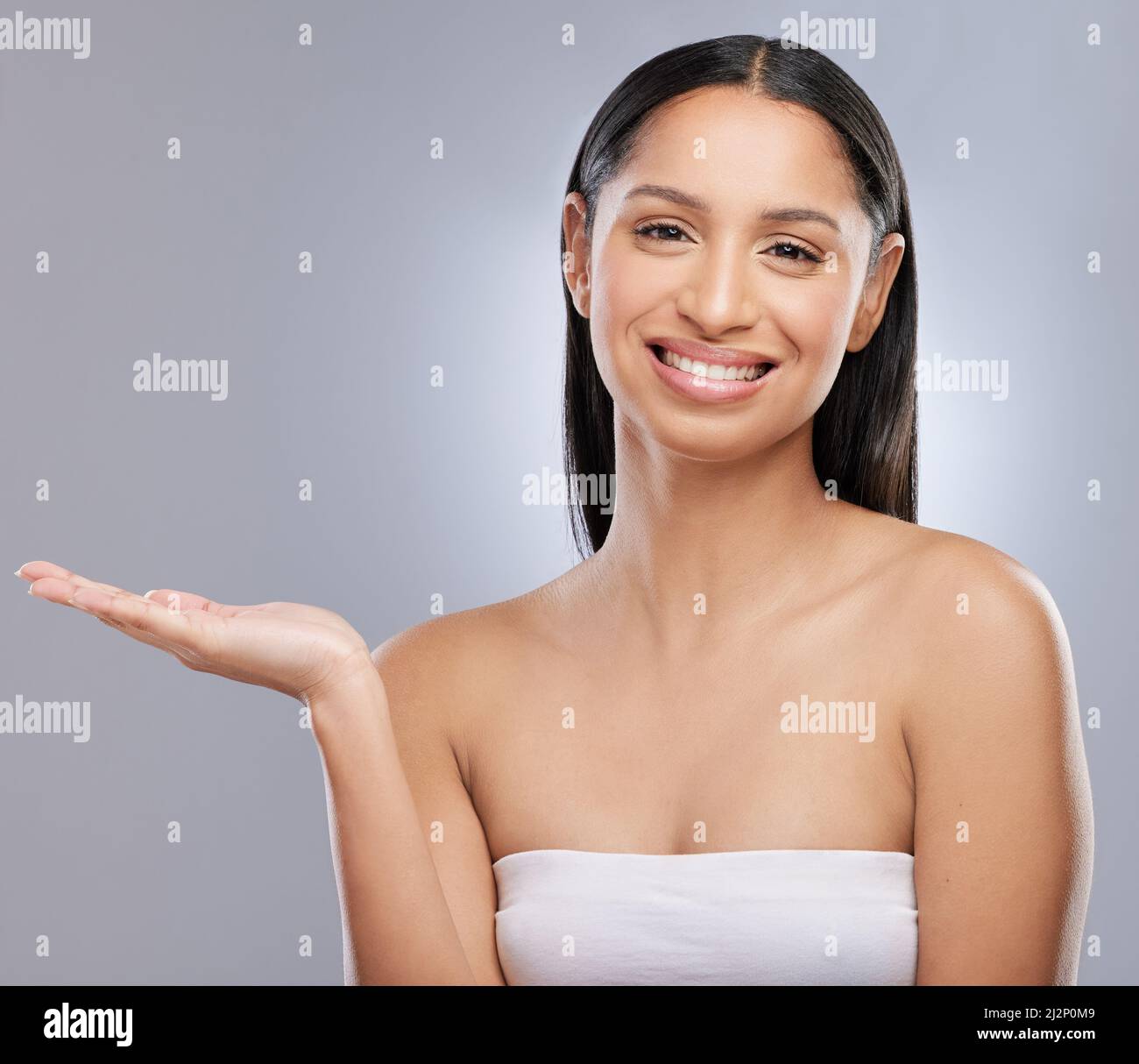 Was habe ich hier Studioaufnahme einer schönen jungen Frau, die ihre Hand vor einem grauen Hintergrund ausstreut. Stockfoto