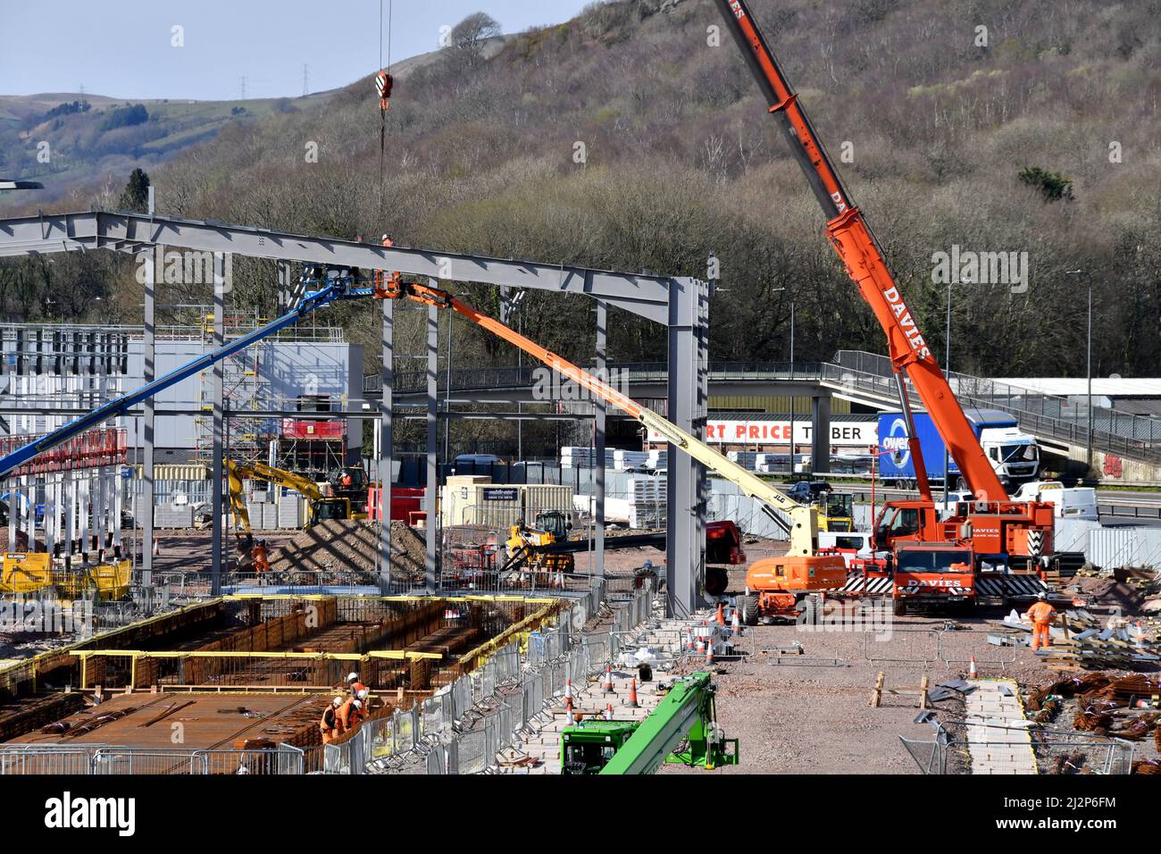 Taffs Well, in der Nähe von Cardiff, Wales - März 2022: Mobiler Kran, der Teile des Stahlrahmens für ein neues Bahndepot hebt. Stockfoto