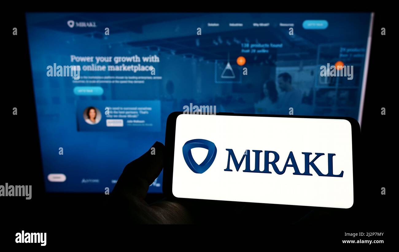 Person, die Smartphone mit Logo des französischen E-Commerce-Software-Unternehmens Mirakl auf dem Bildschirm vor der Website hält. Konzentrieren Sie sich auf die Telefonanzeige. Stockfoto