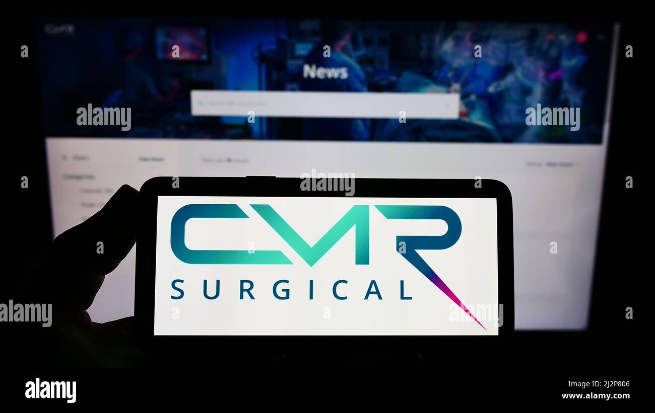 Person, die das Smartphone mit dem Logo des Medizintechnikunternehmens CMR Surgical Ltd. Auf dem Bildschirm vor der Website hält. Konzentrieren Sie sich auf die Telefonanzeige. Stockfoto
