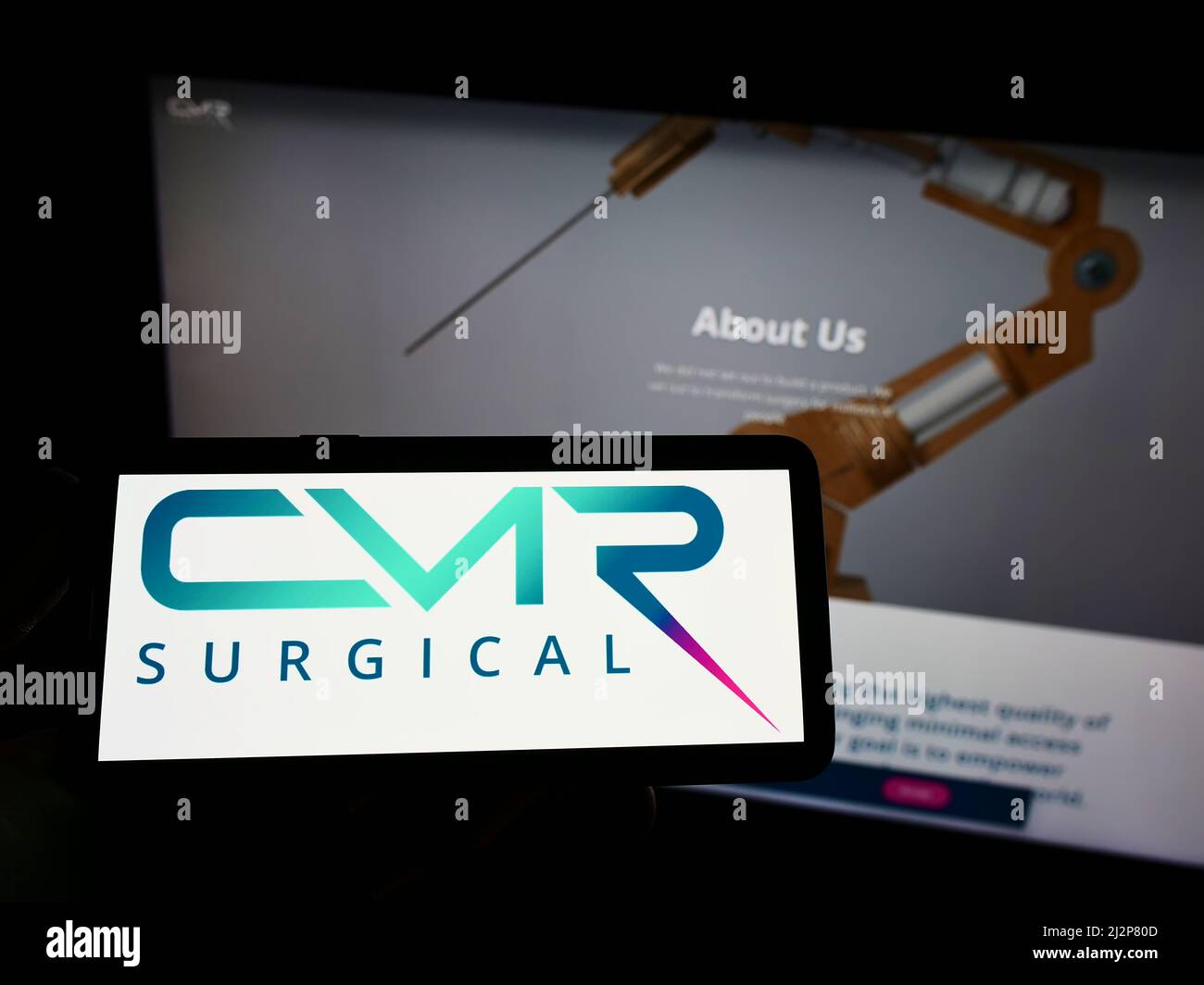 Person, die das Mobiltelefon mit dem Logo des Medizintechnikunternehmens CMR Surgical Ltd. Auf dem Bildschirm vor der Webseite hält. Konzentrieren Sie sich auf die Telefonanzeige. Stockfoto