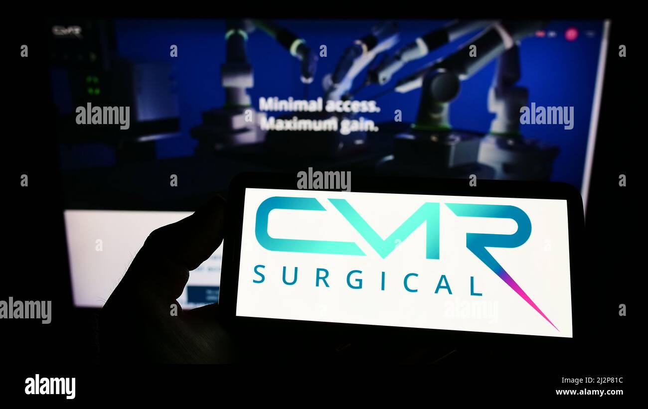 Person, die Mobiltelefon mit dem Logo des Medizintechnikunternehmens CMR Surgical Ltd. Auf dem Bildschirm vor der Business-Webseite hält. Konzentrieren Sie sich auf die Telefonanzeige. Stockfoto
