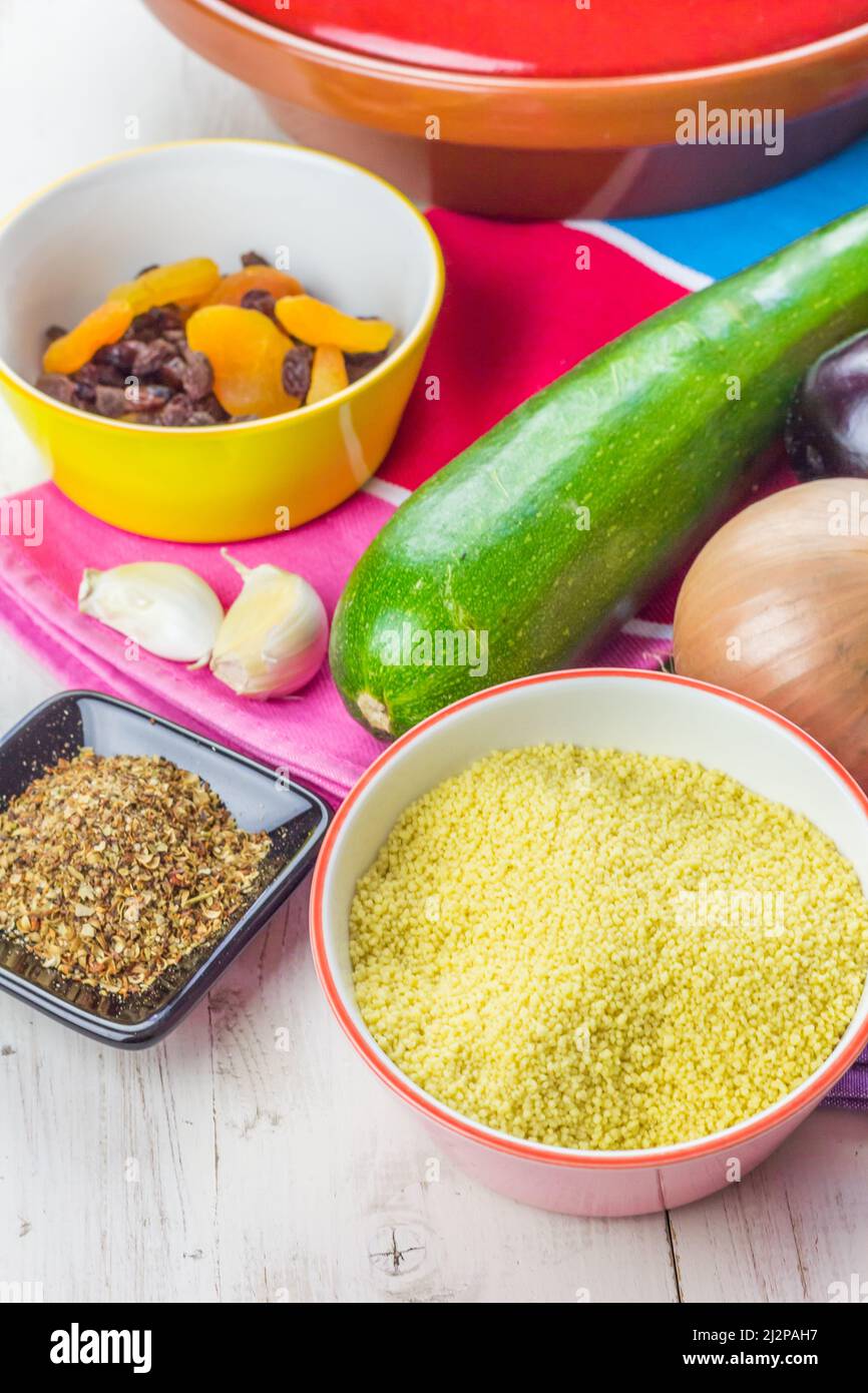 Marokkanischer Couscous mit Gemüse, Gewürzen und getrockneten Früchten auf einem bunten Tischtuch Stockfoto