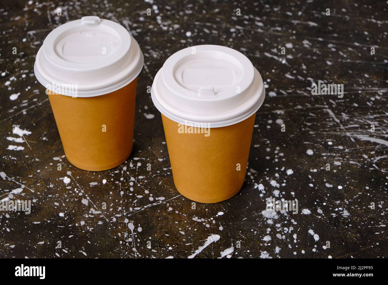 Zwei Papierkaffee-Einwegbecher auf schmutzigem Boden Stockfoto