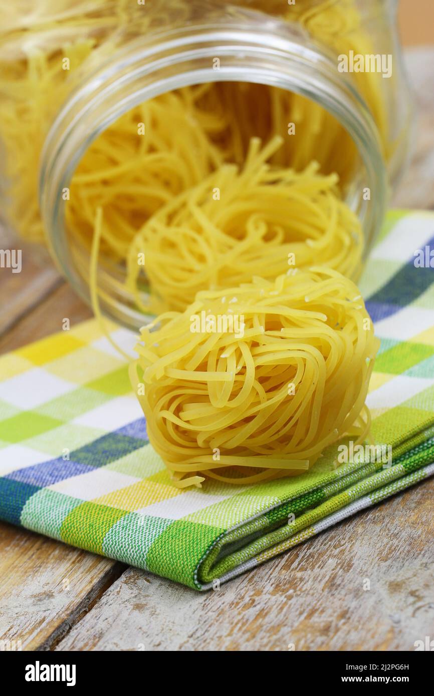 Ungekochte italienische Tagliatelle Nester auf buntem Küchentuch Stockfoto