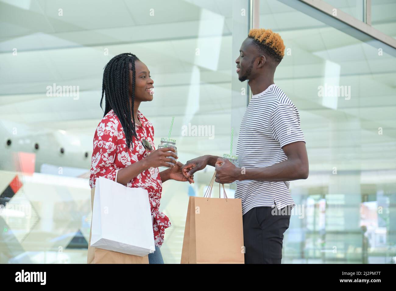 Junges afrikanisches Paar trinkt erfrischende Getränke und geht einkaufen. Stockfoto