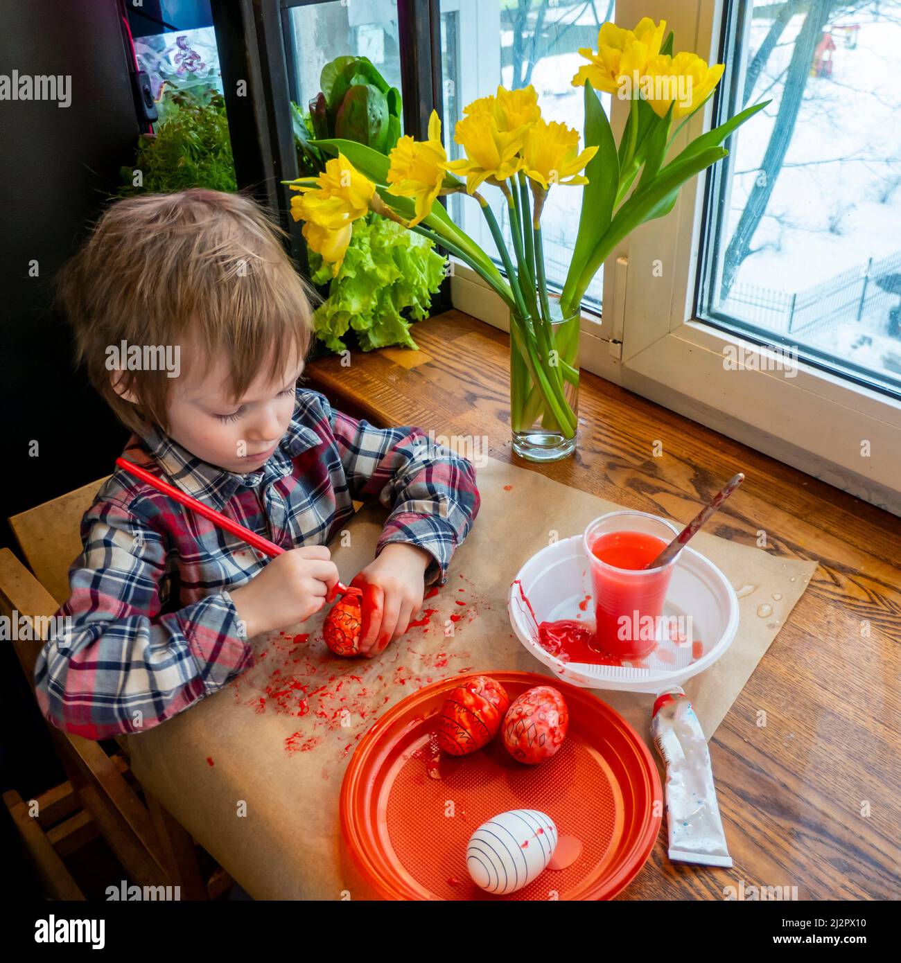 Das Kind bereitet sich auf Ostern vor. Eier bemalen. Rot gefärbte Eier. Stockfoto
