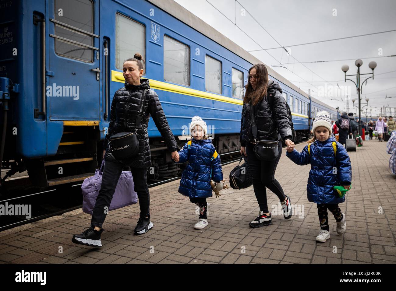 LVIV, UKRAINE - APR 02, 2022: Krieg in der Ukraine. Flüchtlinge - Zwillingsmädchen, Mutter und Großmutter aus dem Evakuierungszug aus Mariupol, Berdyansk, Kryvyi Rih, Stockfoto