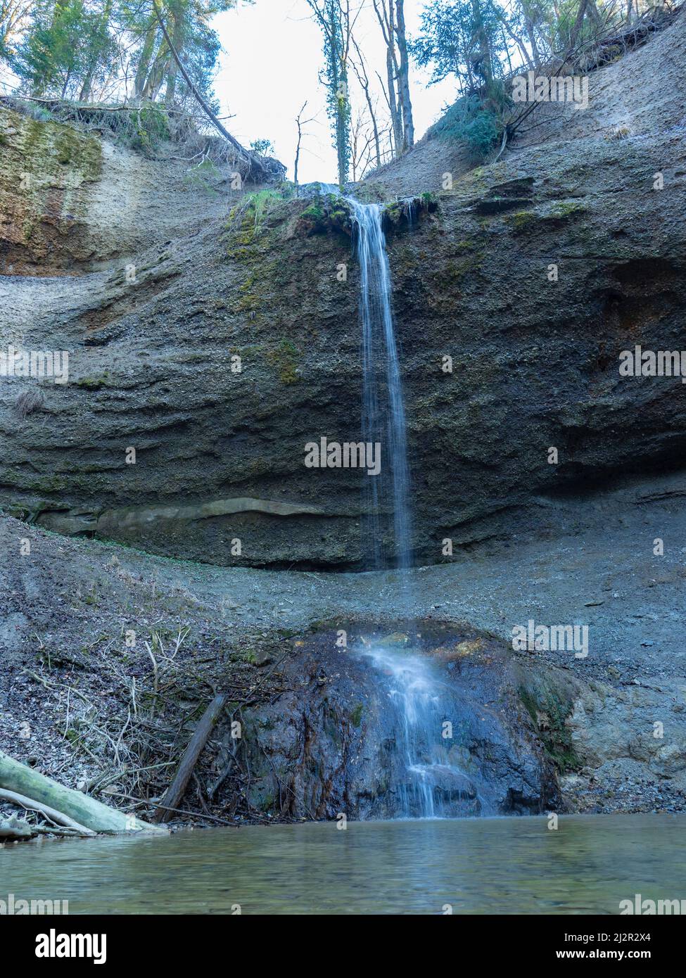 Ein kleiner Wasserfall über einer Felswand inmitten eines Waldes rund um Zürich, Schweiz Stockfoto