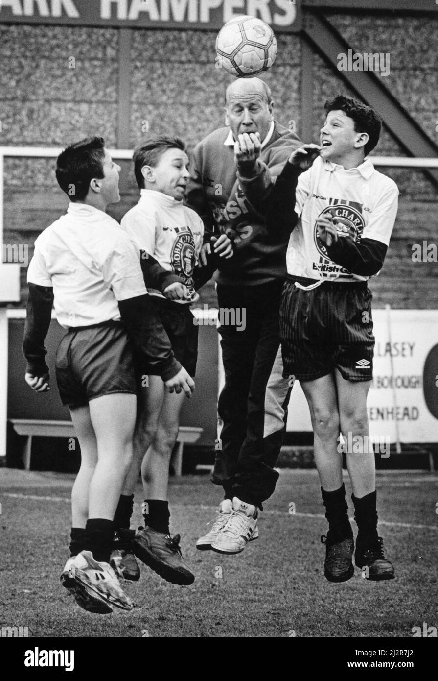 Bobby Charlton stellte das Training mit Schuljungen der Bebington High School, der Wirral, Liverpool, Merseyside vor. Von links nach rechts sind Stephen Swanick, Carl Houghton und Kevin Davies, alle 12 Jahre alt. Bild aufgenommen am 5.. März 1993 Stockfoto