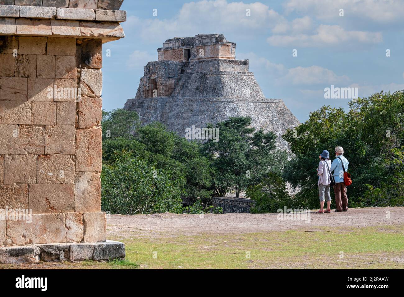 Uxmal archäologische Stätte, Yucatan Mexiko: Zwei Touristen betrachten die Pyramide des Magiers, berühmte antike maya-Ruinen, Puuc-Architektur Stockfoto