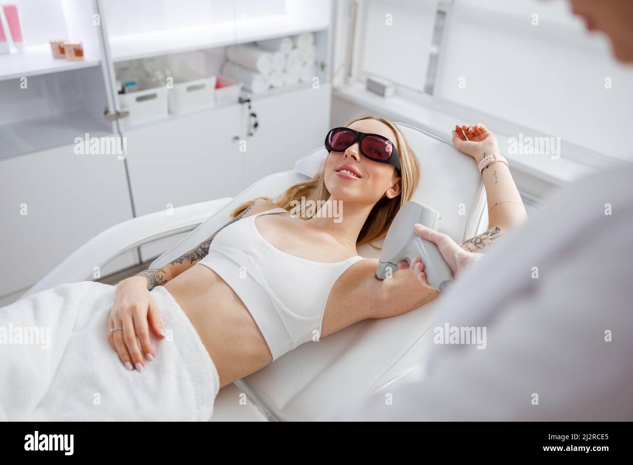 Freudige Frau, die im Schönheitssalon eine Laserepilation erhält Stockfoto