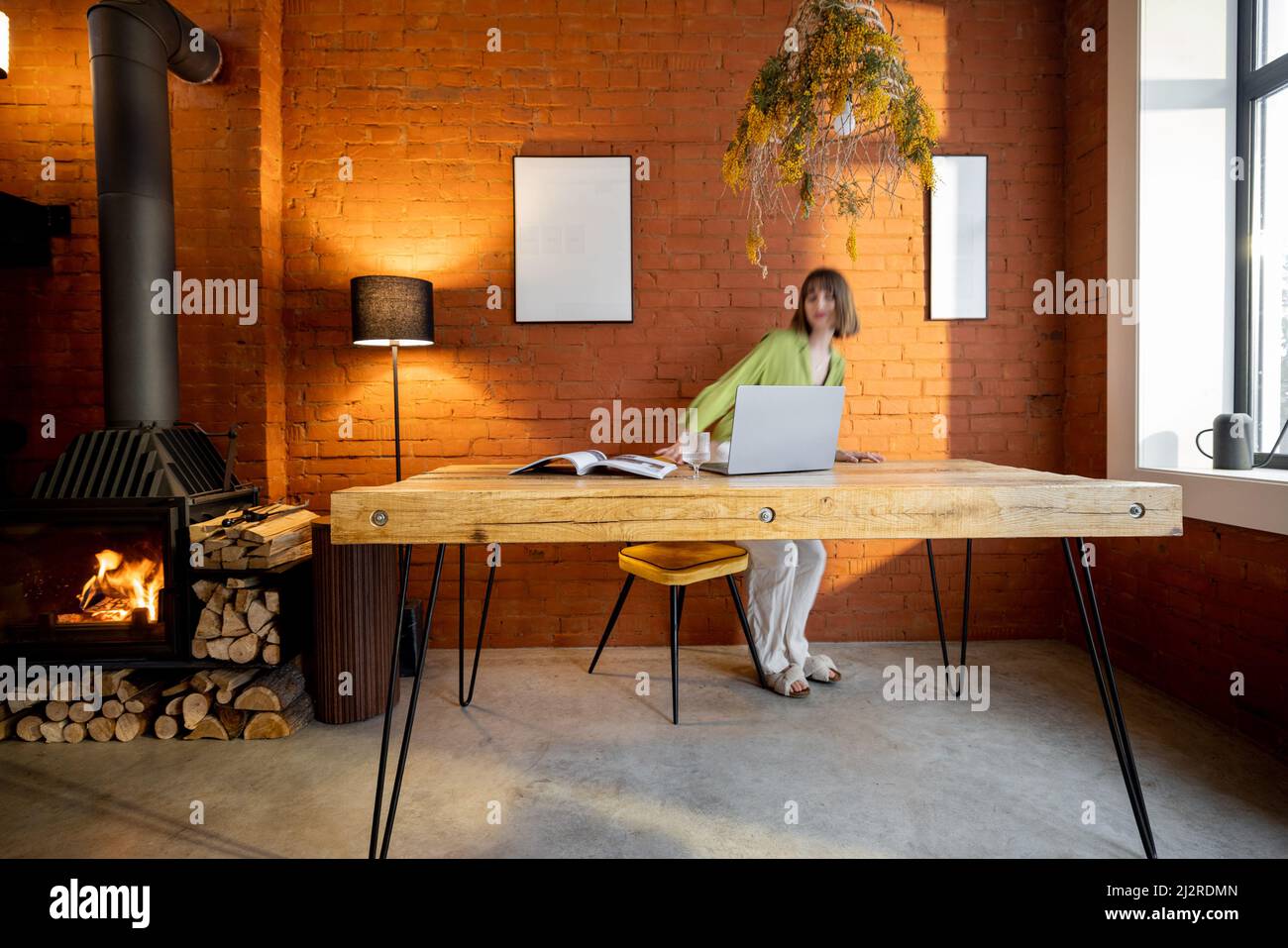 Frau sitzt am Tisch im Wohnzimmer im Loft-Stil Stockfoto