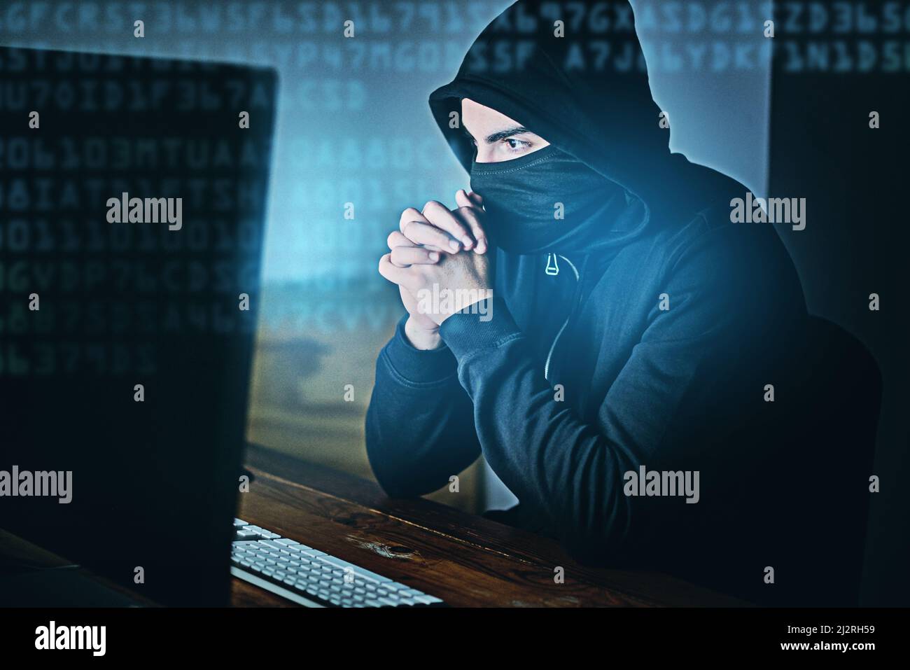 Einige Klicks und du hacked. Aufnahme eines jungen Hackers, der spät in der Nacht einen Computer benutzt. Stockfoto