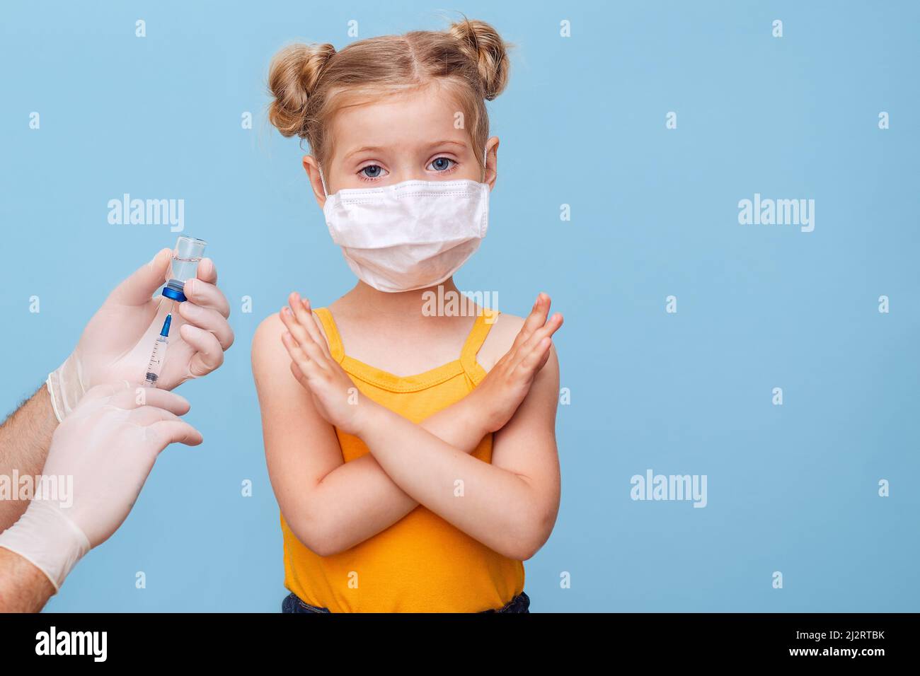 Ein Arzt impft ein kleines blondes Mädchen mit einer medizinischen Maske. Stockfoto