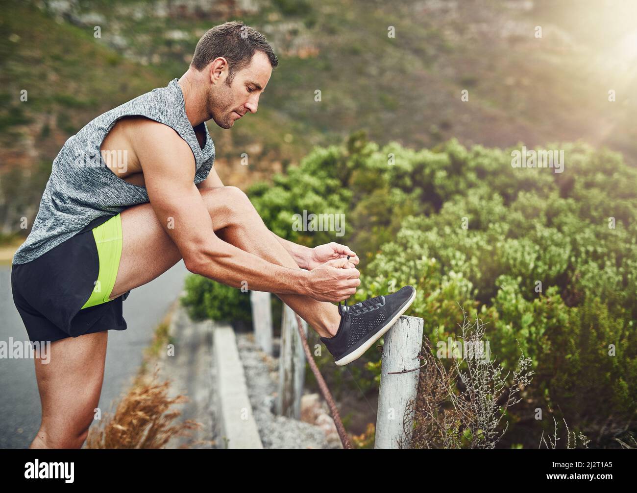 Er fessele seine Schnürsenkel. Aufnahme eines jungen, hübschen Mannes, der im Freien für einen Marathon trainiert. Stockfoto