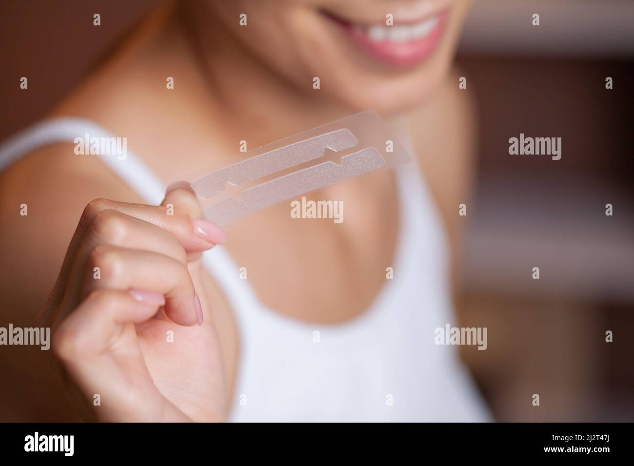 Schöne junge Mädchen mit weißen Zähnen halten in den Händen Streifen für Zahnaufhellung Stockfoto