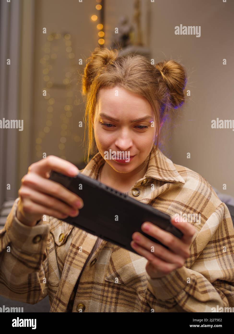 Ein Teenager-Mädchen spielt ein mobiles Spiel auf einer tragbaren Spielkonsole. Nahaufnahme. Das Mädchen schaut aufmerksam auf den Bildschirm. Leidenschaft, Unterhaltung, Erholung Stockfoto