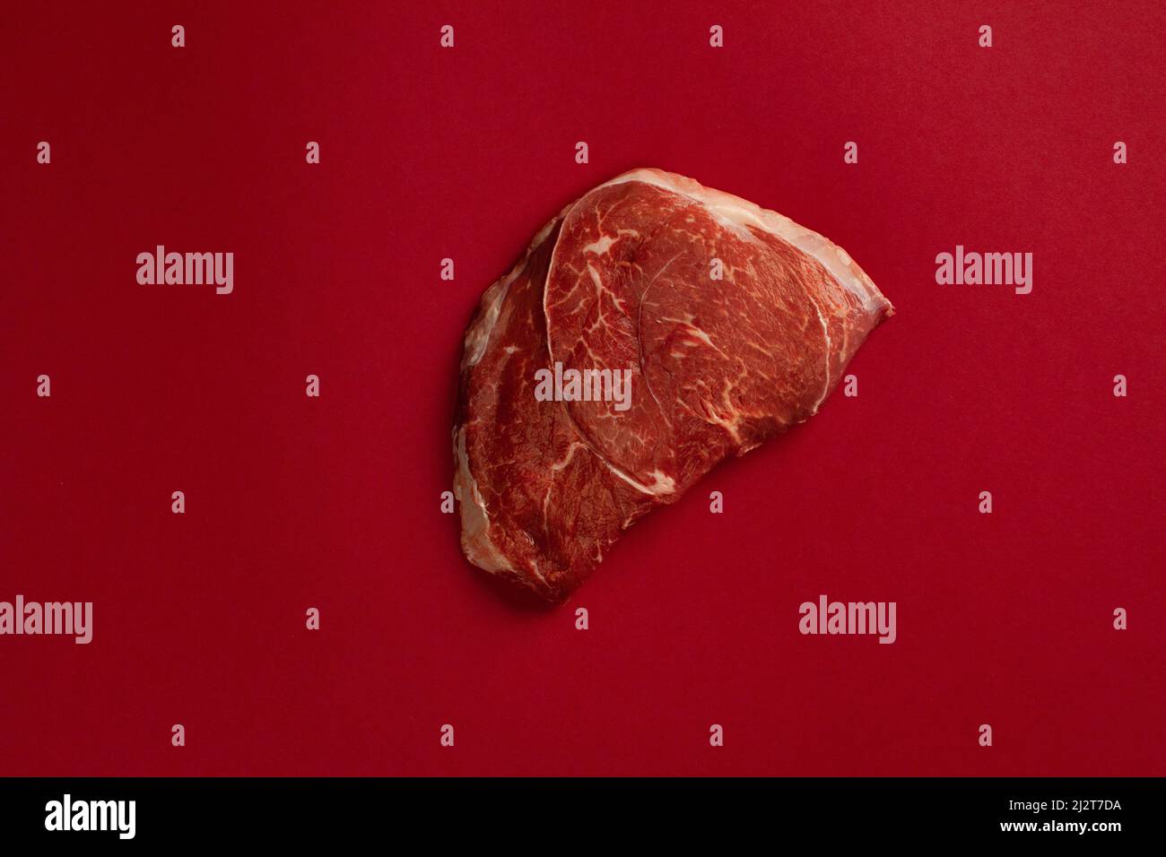 Rohes Rinderfleischsteak isoliert auf einem Bluthintergrund Stockfoto