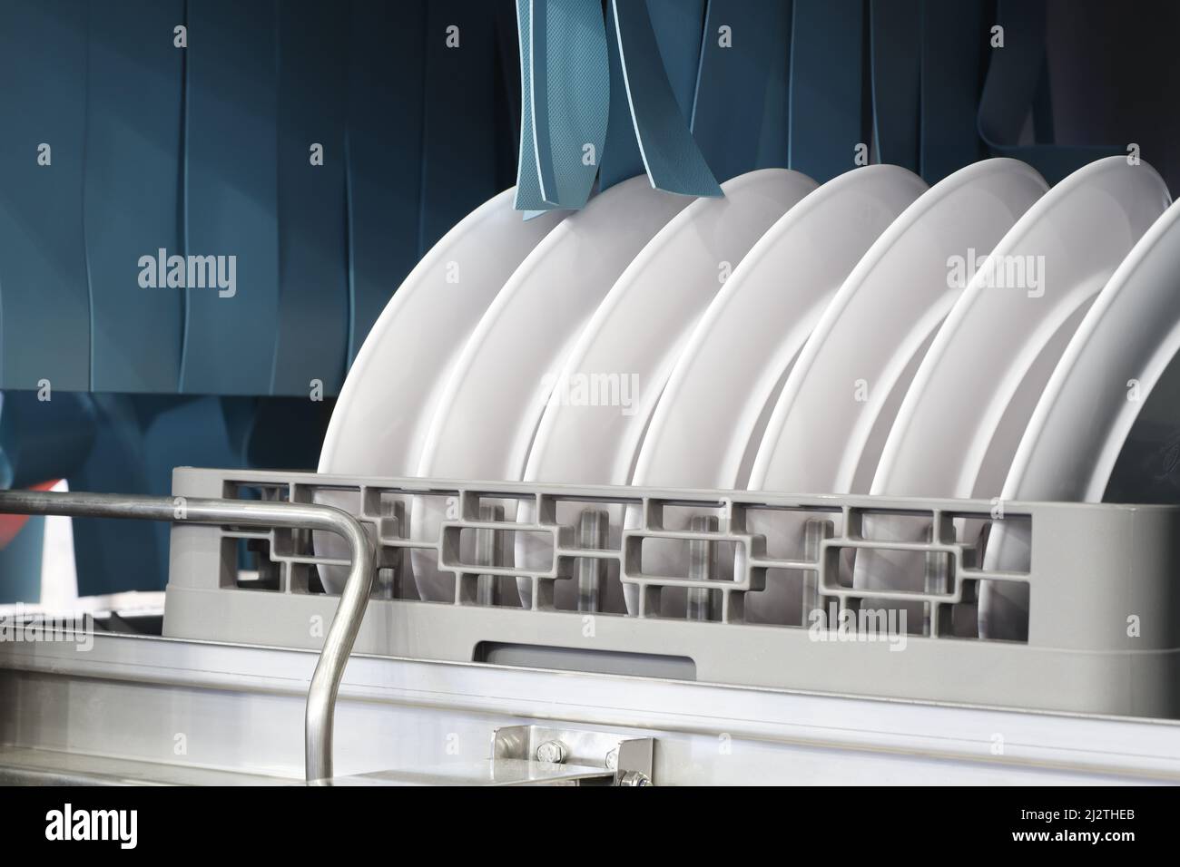 Die automatische Spülmaschine mit weißen, sauberen Gerichten im Korb. Für Restaurant. Geschäftlicher industrieller Hintergrund Stockfoto