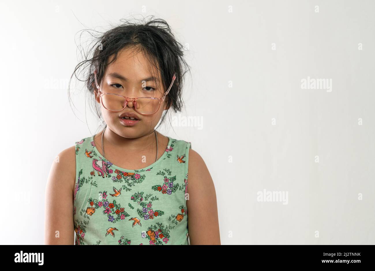 Portrait Asian Kind Mädchen mit chaotischen Frisur, öliges Gesicht, hängende Brille auf dem Gesicht, flimmernde Augen, Gefühl von erschöpft von Überlastung Studiein Stockfoto