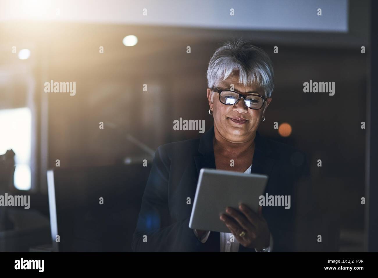 Digitale Geschäftsbeziehungen nach Einbruch der Dunkelheit. Aufnahme einer reifen Geschäftsfrau, die spät in der Nacht ein digitales Tablet in einem modernen Büro verwendet. Stockfoto