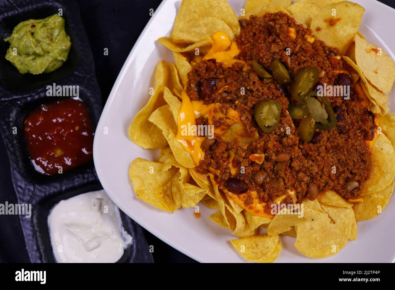 Traditionelle mexikanische Snacks, Mais-Tortilla-Chips und Avocado-Guacamole, Chili con Carne, Salsa und saure Creme. Bekannt als Nachos Stockfoto