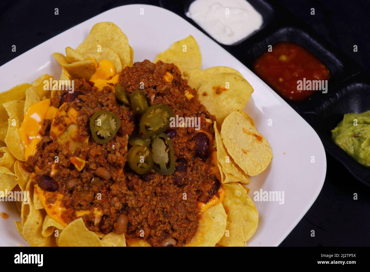 Traditionelle mexikanische Snacks, Mais-Tortilla-Chips und Avocado-Guacamole, Chili con Carne, Salsa und saure Creme. Bekannt als Nachos Stockfoto