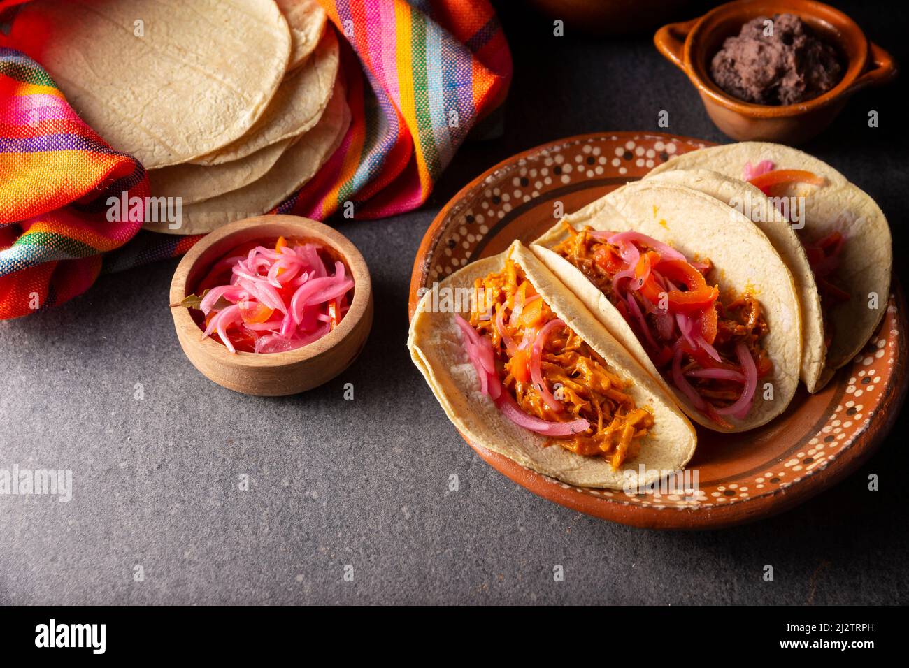 Tacos de Cochinita Pibil. Typisch mexikanischer Eintopf aus Yucatan, hergestellt aus Schweinefleisch, mariniert mit Achiote und in der Regel mit Bohnen und roten Zwiebeln begleitet Stockfoto