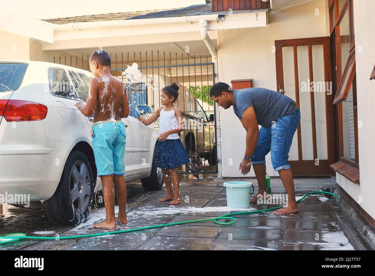 Macht die Arbeit Spaß. Aufnahme einer Familie, die draußen ein Auto gemeinsam wäscht. Stockfoto