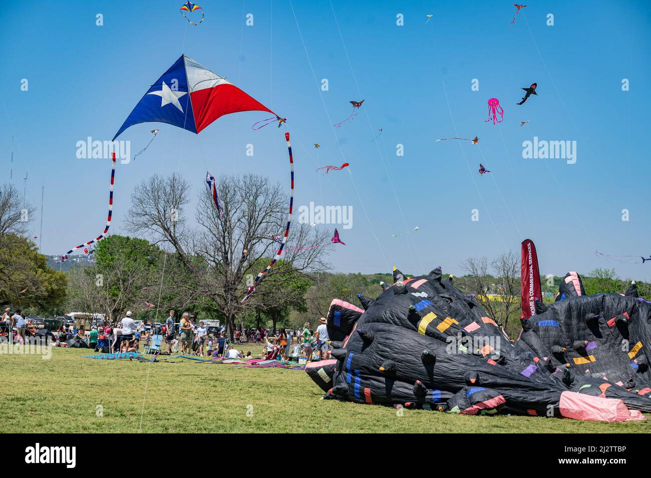 Austin, Texas, USA. 3. April 2022. Ein großer Drachen, auf dem die Texas-Flagge prangt, stellt leicht die anderen Drachen am Himmel in den Schatten. Das ABC Kite Festival 93. kehrte am Sonntag in den Zilker Park zurück. Tausende von Besuchern flogen bunte Drachen über den 350 Hektar großen Park. Kredit: Sidney Bruere/Alamy Live Nachrichten Stockfoto