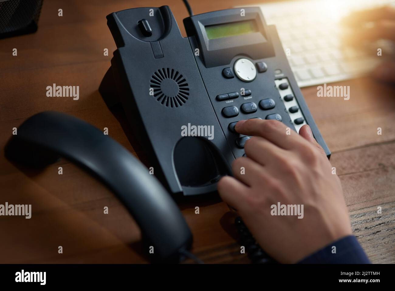 Tätigen Sie diesen Anruf. Zugeschnittene Aufnahme eines nicht erkennbaren Mannes, der eine Nummer auf einem Telefon anwählt. Stockfoto