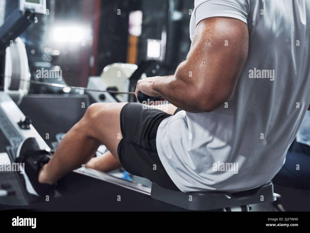 Arbeitet seinen ganzen Körper. Zugeschnittenes Bild eines nicht erkennbaren männlichen Athleten, der im Fitnessstudio auf einem Rudergerät trainieren soll. Stockfoto