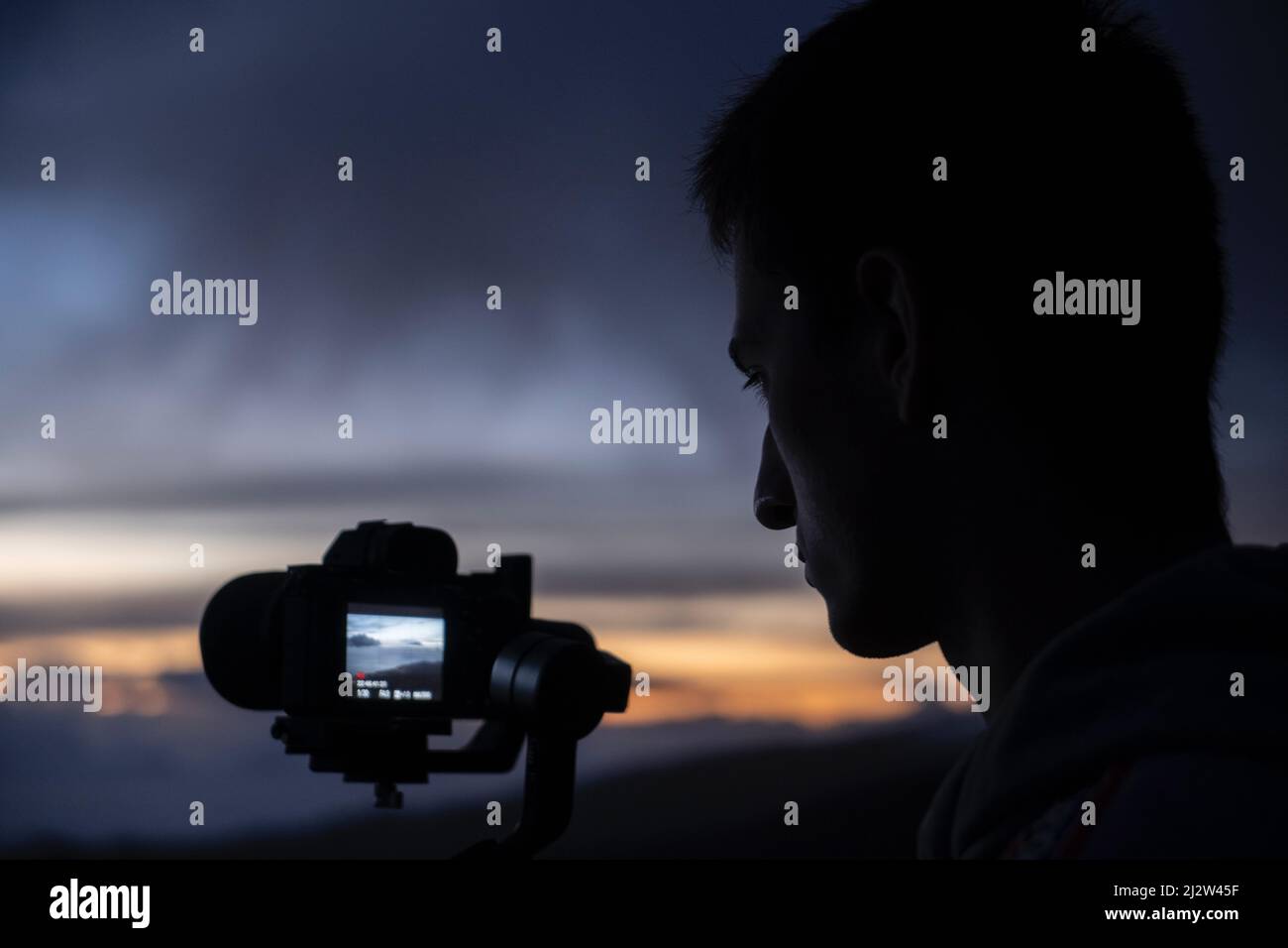 Mann, der einen Sonnenuntergang filmt Stockfoto