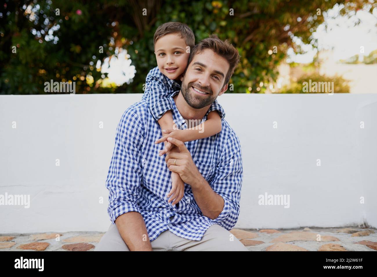 Hes ein kleines Mini Me. Beschnittenes Porträt eines hübschen jungen Mannes und seines Sohnes, die draußen sitzen. Stockfoto