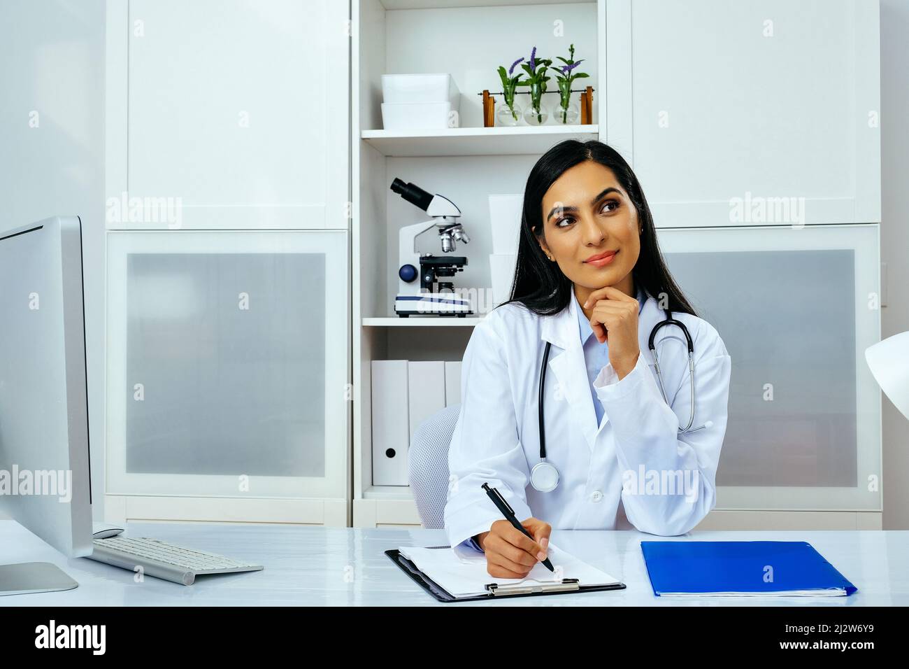 Porträt einer schönen jungen Ärztin in weißem Laborkittel Uniform arbeiten am Schreibtisch in ihrem modernen Büro Gesundheitswesen industy Stockfoto