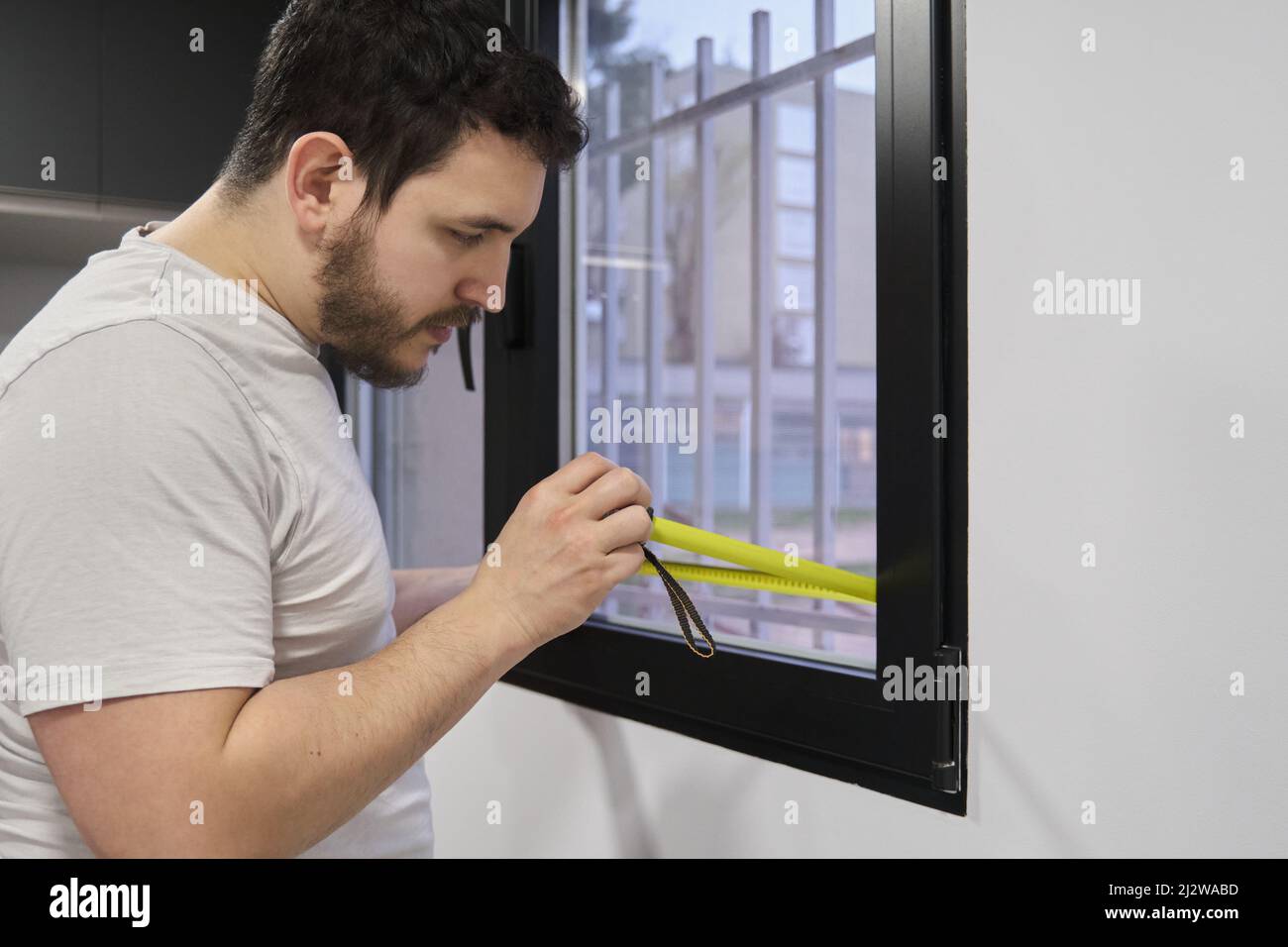 Mann, der Fensterglas misst, um mattiertes Fenstervinyl zu installieren. Stockfoto