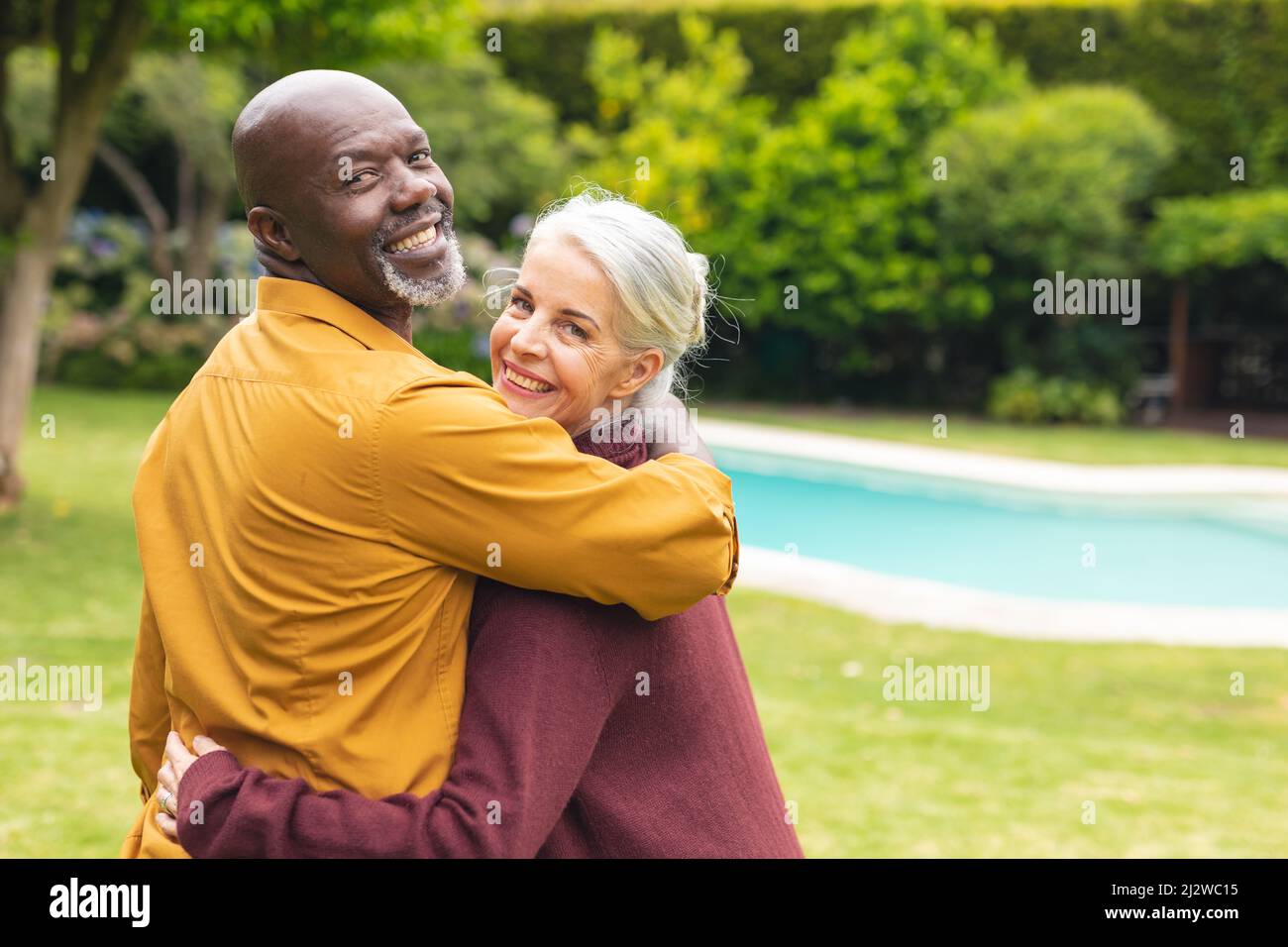 Porträt eines glücklichen multirassischen älteren Paares, das im Hinterhof über die Schultern schaut Stockfoto