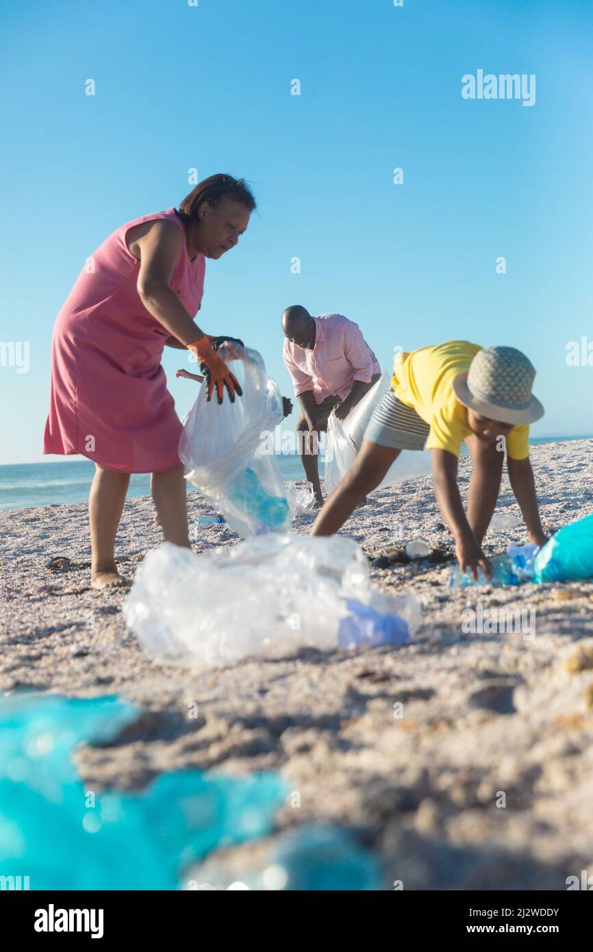 afroamerikanische Großeltern und Enkelkinder sammeln Plastikmüll am Strand mit Kopierplatz Stockfoto
