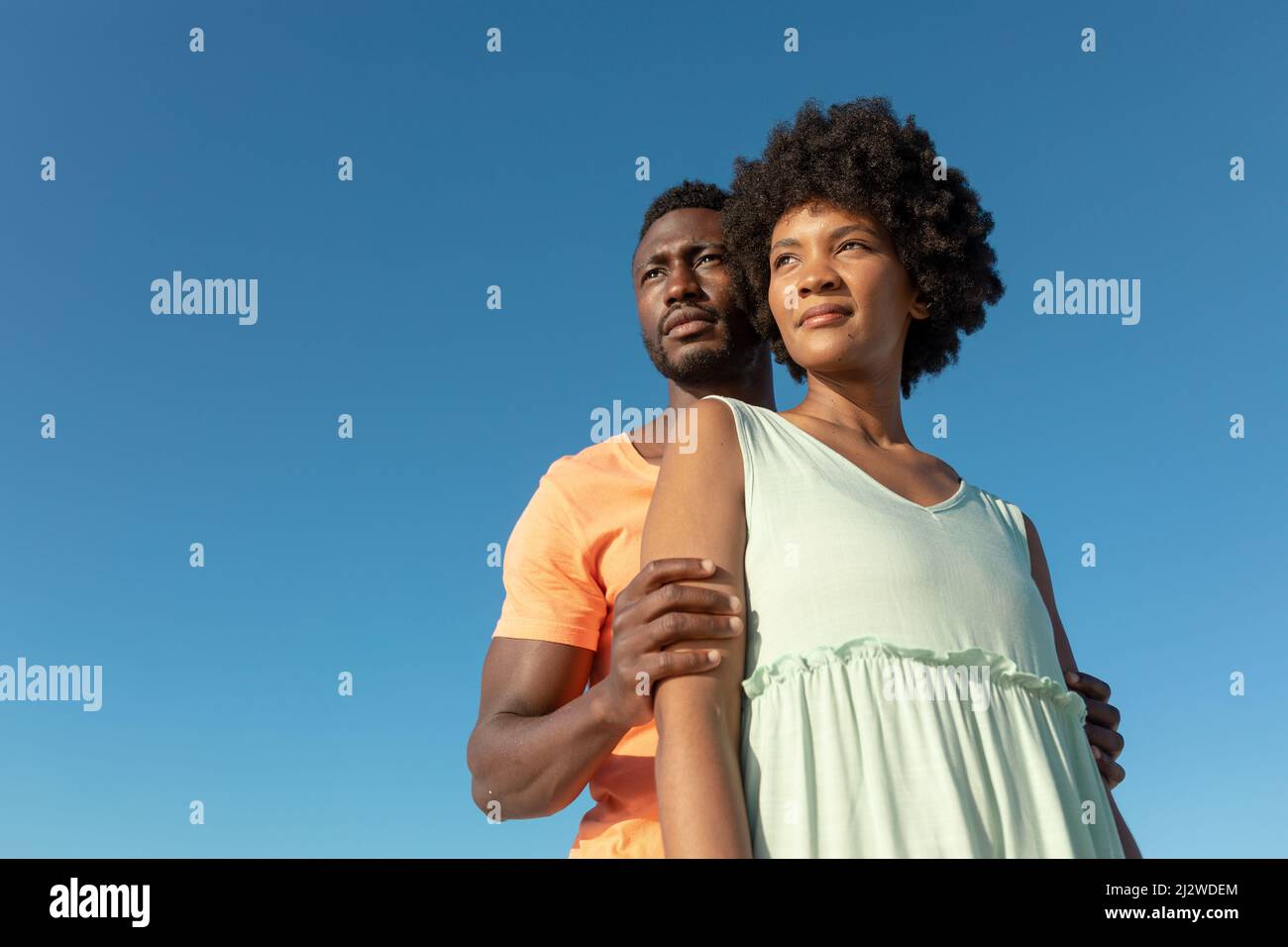 Low-Angle-Ansicht des afroamerikanischen Paares, das vor einem klaren blauen Himmel mit Kopierraum steht Stockfoto